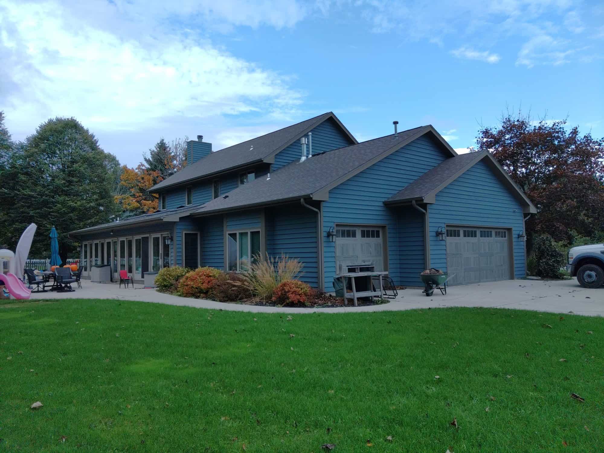 Large dark blue house with stone walkway and two garages