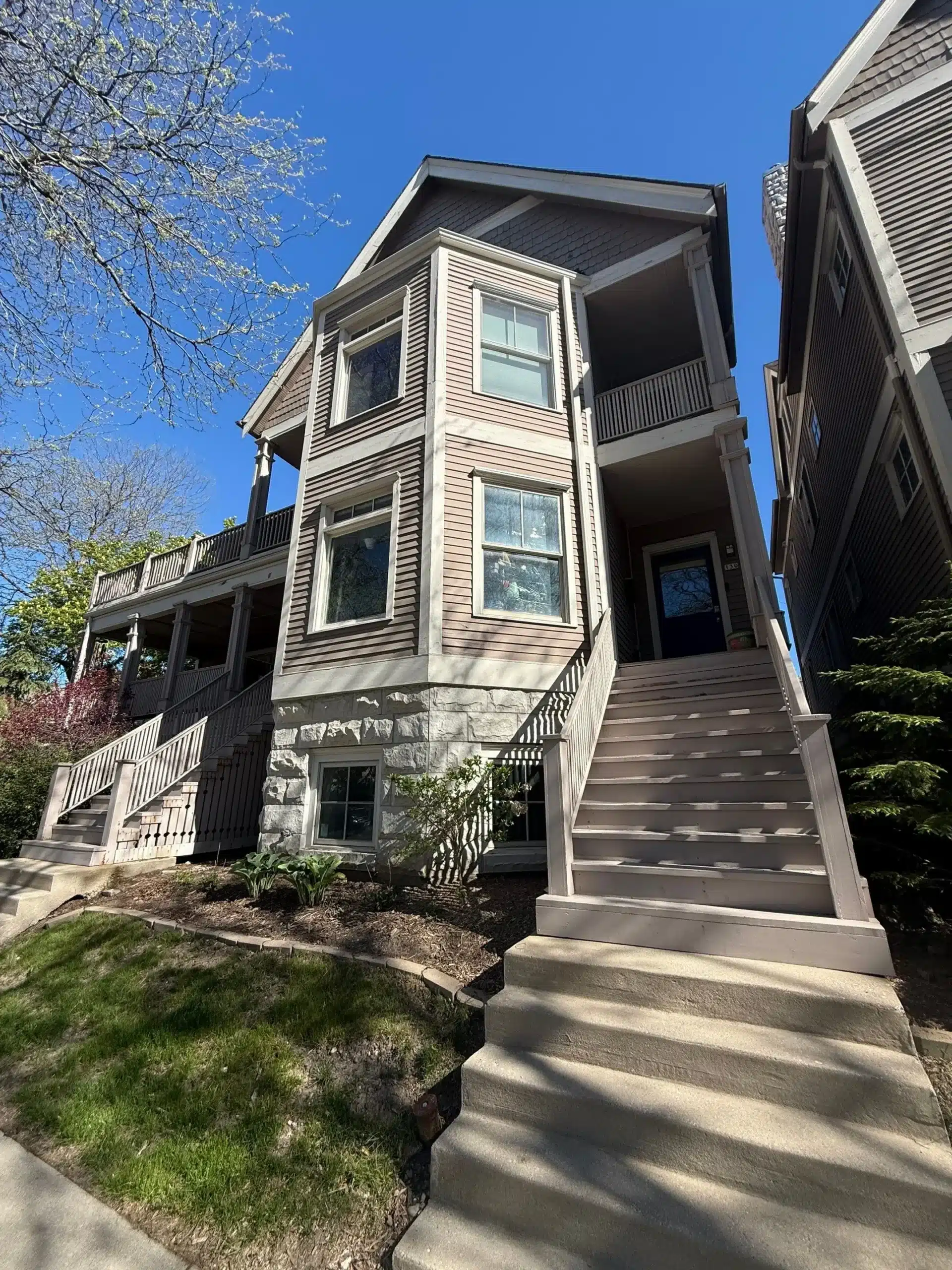 Expert Exterior Painting for Multi Family Residential Buildings A multi story residential building featuring brown siding, white trim, bay windows, and prominent outdoor staircases.